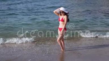 穿着红色<strong>泳装</strong>的女人站在海滩上的水里。